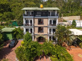 Un edificio de varios pisos con balcones, techo verde y entrada pavimentada.