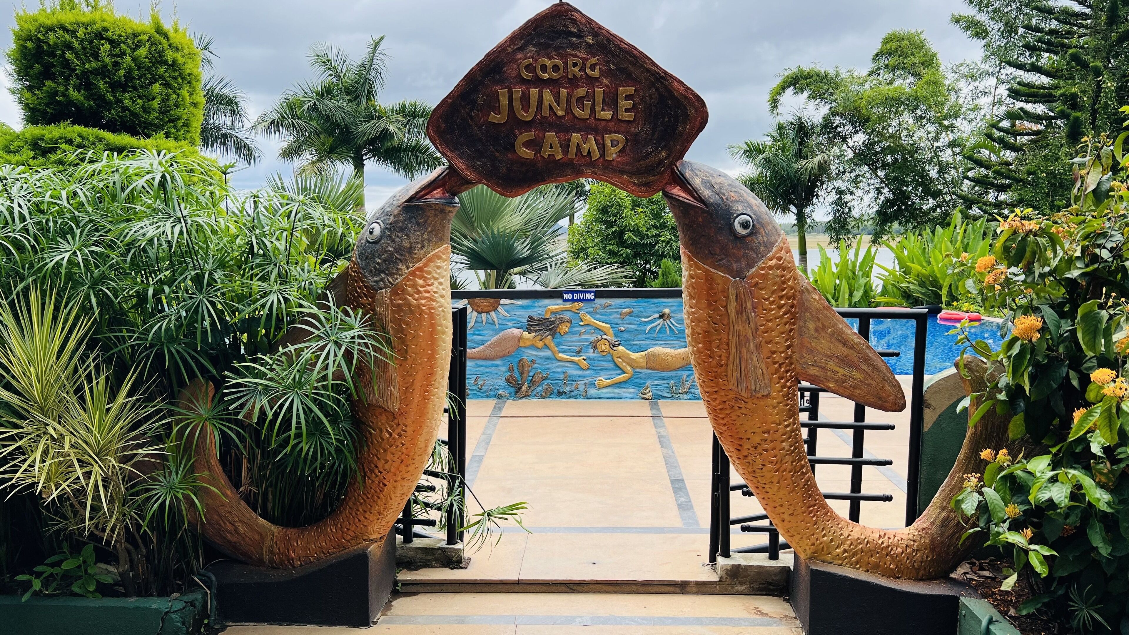 A large fish-shaped archway with a sign reading "Corg Jungle Camp" and a "No Diving" sign below it.