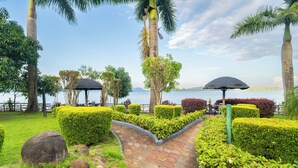 Un jardin aménagé avec un sentier dallé, des palmiers et une vue sur l’eau.