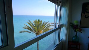 Een kamer met een groot raam met uitzicht op een strand en de oceaan.