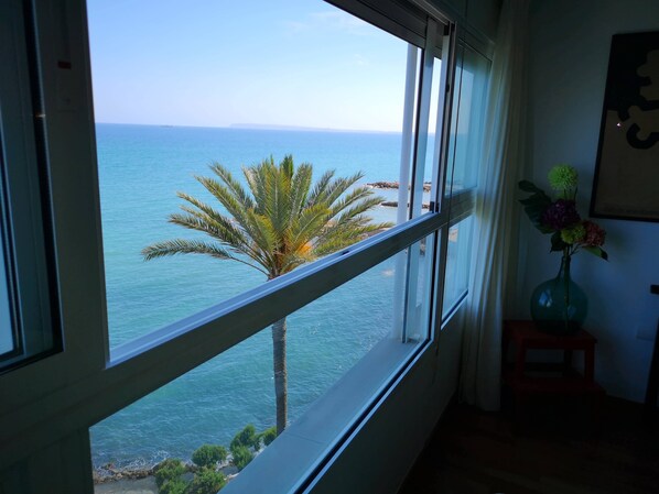 A room with a large window overlooking a beach and ocean.