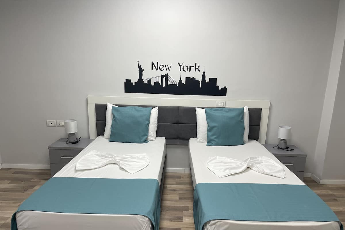 Een hotelkamer met twee bedden, stadszicht als wanddecoratie, en een modern design.