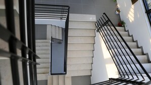 Una escalera moderna con barandillas negras y plantas en macetas en el rellano.