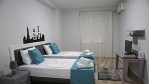 Habitación de hotel con dos camas, un escritorio, un televisor y un adorno en la pared.