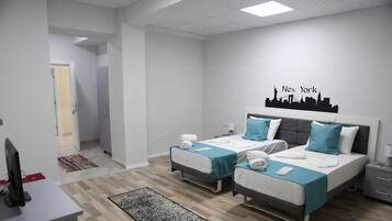 A modern hotel room with two beds, a desk, and a city skyline wall art.