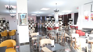 Un interior moderno con diversas opciones de asientos, incluyendo mesas y sillas, y una zona central con un elemento decorativo.