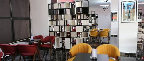 Ein modernes Interieur mit Schwarz-Weiß-Farbgebung, das eine Sitzecke mit gelben Stühlen, einem schwarzen Tisch und einem Bücherregal mit verschiedenen Gegenständen zeigt.