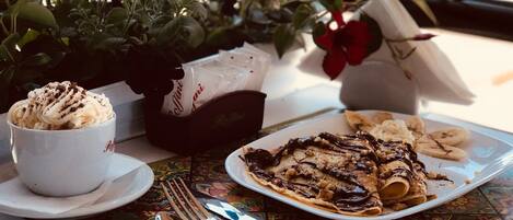 Une table avec une assiette de nourriture, une tasse de café et un vase de fleurs.