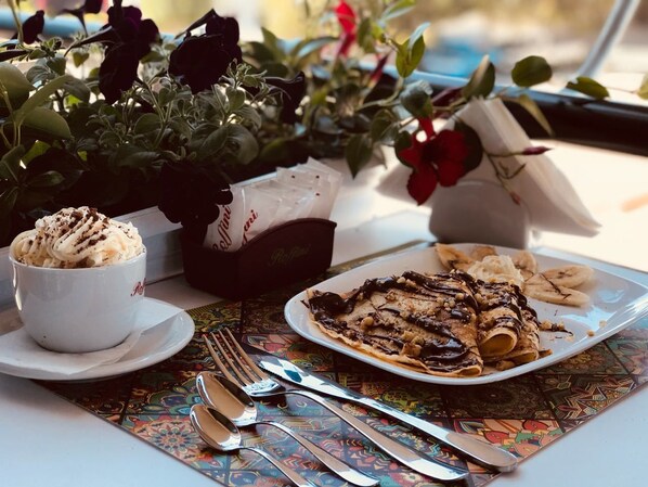 A table with a plate of food, a cup of coffee, and a vase of flowers.