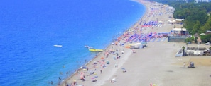 A beach with numerous umbrellas and people.