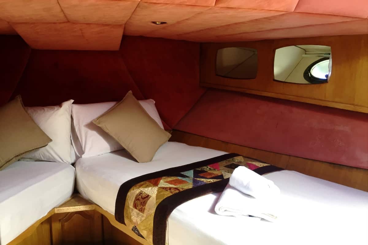 A compact cabin with two beds, a quilt, and a mirror.
