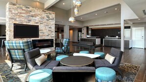 Ein moderner Lounge-Bereich mit Steinwand, bequemen Sitzgelegenheiten, einem Flachbildfernseher und einer Bar.