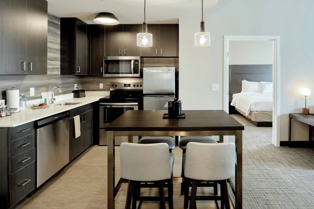 A modern kitchen with dark wood cabinets, stainless steel appliances, and a central island with bar stools.