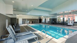 Ein moderner, überdachter Pool mit Liegestühlen, einem Sprungverbotsschild und freiem Blick ins Freie.