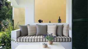Ein moderner Außenbereich zum Sitzen mit einem weißen Tisch und einer gepolsterten Bank.