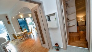 Moderni sisustus, jossa on ruokailutila, keittiö ja eteinen, joka johtaa makuuhuoneeseen.
