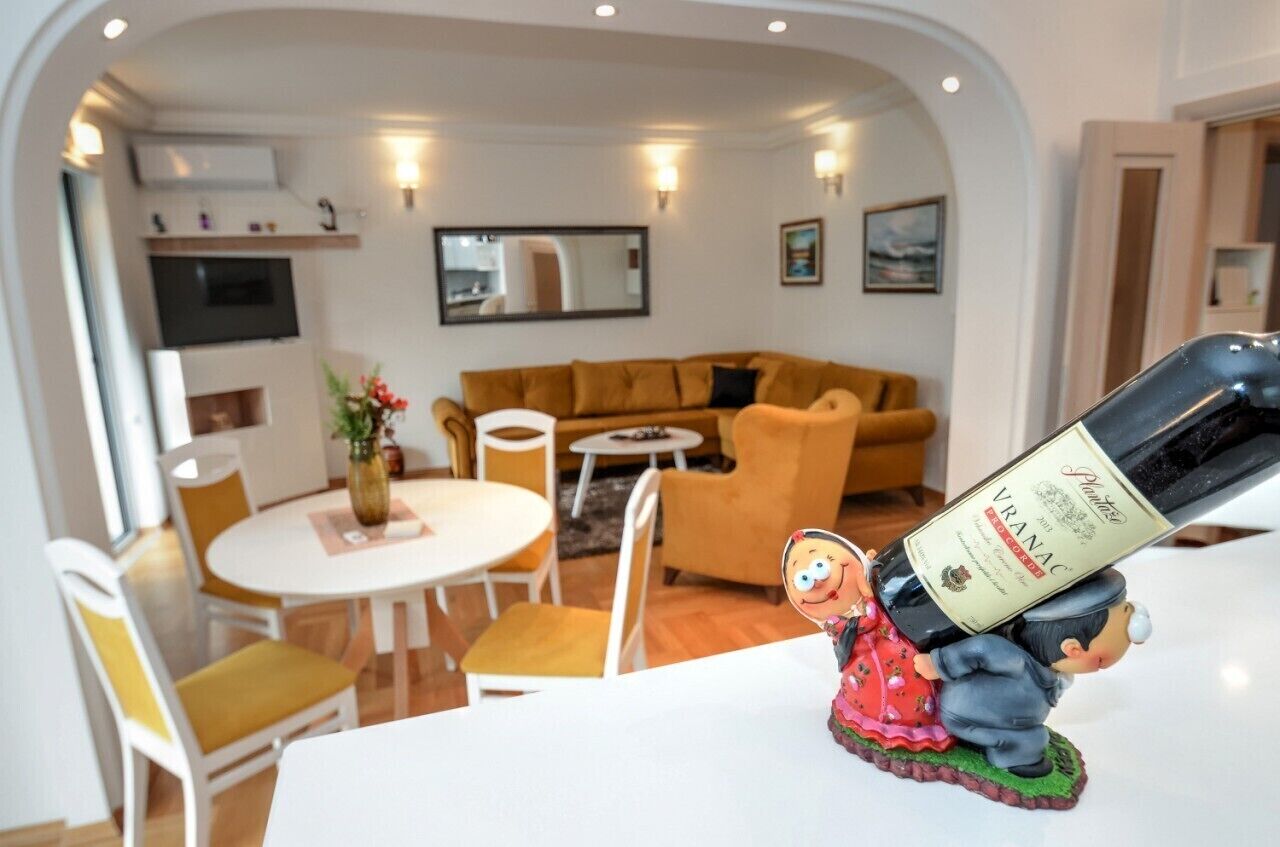 A cozy living room with a sofa, a dining table with chairs, and a TV mounted on the wall.