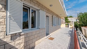 Un bâtiment doté d’une façade en pierre, de volets blancs et d’un trottoir dallé.