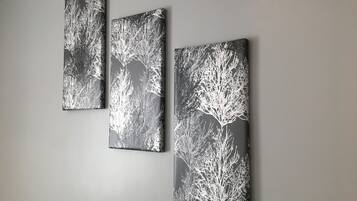Three wall-mounted artworks depicting abstract tree branches on a grey wall.