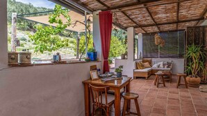 Un patio acogedor con mesa y sillas de madera, un sofá y plantas en macetas.