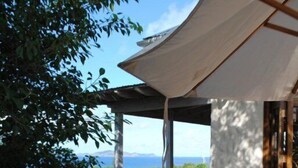 A covered outdoor seating area with white chairs and a table, overlooking a scenic view. - Rockmere Villa - PANORAMIC OCEAN VIEWS, BEACH .2 MILES, MULTI-UNIT ESTATE (The Baths)