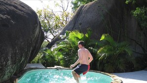 A man in a swimming pool with large rocks and tropical plants around. - Rockmere Villa - PANORAMIC OCEAN VIEWS, BEACH .2 MILES, MULTI-UNIT ESTATE (The Baths)