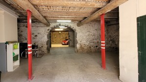 Un étroit passage où l’on aperçoit un vélo, une voiture rouge et une porte verte.