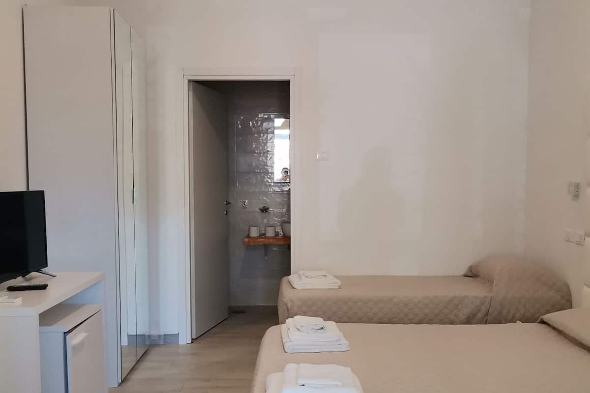 Habitación de hotel minimalista con cama, escritorio y televisor.