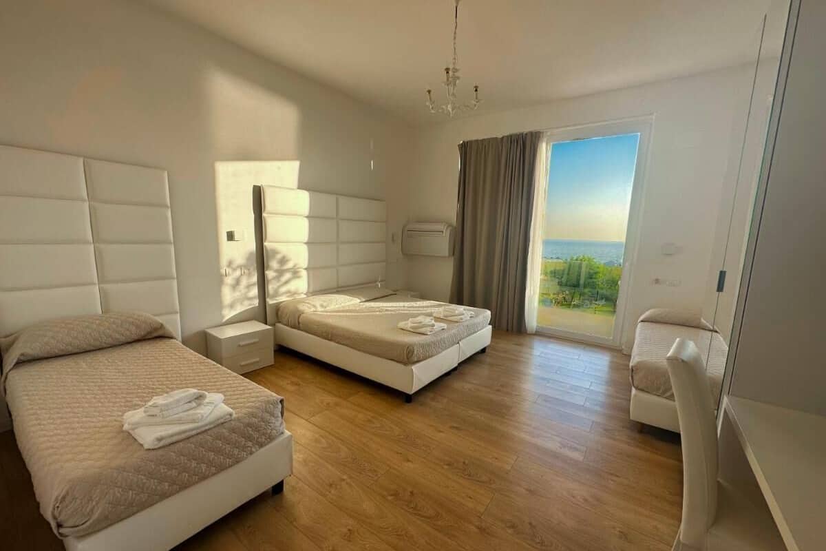 Un dormitorio moderno con dos camas, un escritorio y vistas al exterior.
