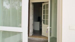 Un interior moderno con un amplio arco que da a una habitación con suelo de madera y un pequeño escritorio.