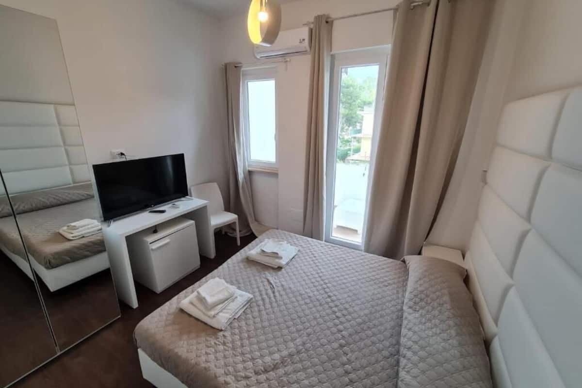 Una habitación de hotel con una cama, televisor, escritorio y una silla.