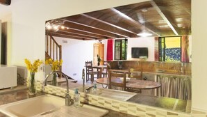 Une cuisine équipée d’un évier, un coin repas avec une table et des chaises, et un bar avec un comptoir et des tabourets.