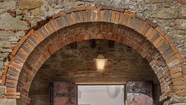 Une entrée en briques en forme d’arc, avec une porte en bois et une petite table à l’intérieur.