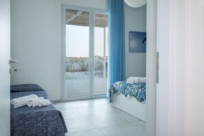 A hotel room with a bed, a second bed, a sliding glass door leading to an outdoor area, and a view of the outside.