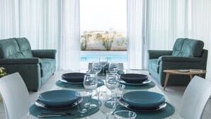 A dining area with a table set for six, two green sofas, and a view of the ocean. - At the home of Giò, villa with pool (Marina di Ragusa)