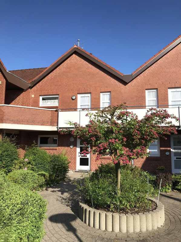Stunning red-brick building with a central entrance, garden, and tree.