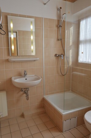 Bathroom features a standalone bathtub, wall-mounted sink, and large mirror.