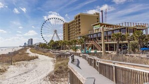 A beachside hotel with a boardwalk, a Ferris wheel, and a modern building with balconies. - Oceanfront W/Long Range Views, 2 bed, 2 bath Penthouse, Large Balcony, Sleeps 6 (Myrtle Beach)