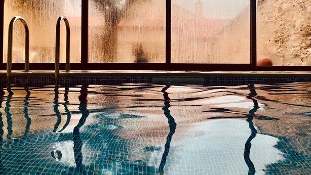 Una piscina con agua cristalina y vistas a través de un ventanal.
