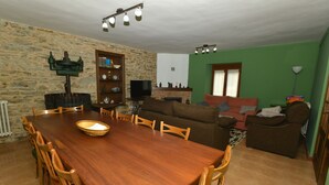 Un comedor con una mesa y sillas de madera, una pared de piedra, una chimenea y una pared verde al fondo.