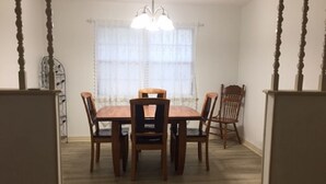 A dining room with a wooden table and chairs, a chandelier, and a window with sheer curtains. - Rural Relaxation in Reklaw! (Reklaw)