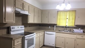 A compact kitchen with beige cabinets, a white stove, and a dishwasher. - Rural Relaxation in Reklaw! (Reklaw)
