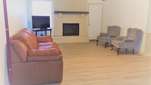 A living room with a brown leather sofa, two armchairs, a fireplace, and a television. - Rural Relaxation in Reklaw! (Reklaw)
