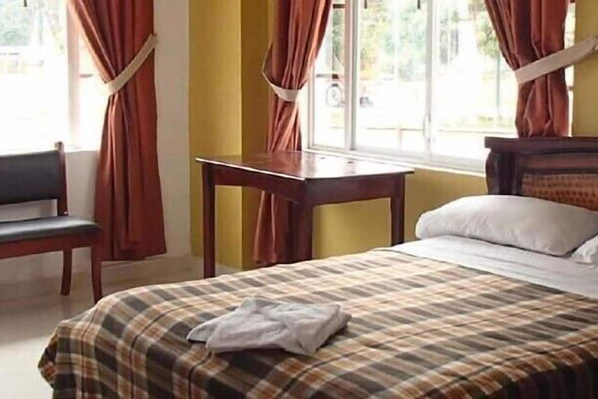 A hotel room with a bed, a desk, and a chair.