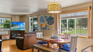 A living room with a television, leather sofa, dining table, and large windows. - Heated pool,4 bedrooms,hot tub, Dogs ok, pond, 2mls to town (Leavenworth)