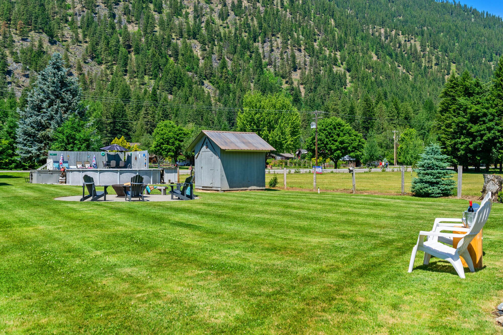 Ein Rasenbereich mit einer kleinen Gartenhütte, einer Grillmöglichkeit und einigen Stühlen.