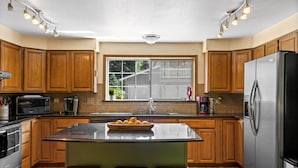 A kitchen with wooden cabinets, a stainless steel refrigerator, a microwave, and a sink. - Heated pool,4 bedrooms,hot tub, Dogs ok, pond, 2mls to town (Leavenworth)