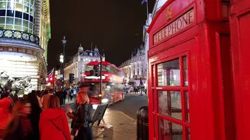A busy street scene with a red telephone booth and a double-decker bus.