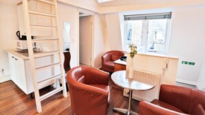 A compact room with a wooden ladder, two brown leather chairs, a small round table, and a window with a view of the city. - Magical & Charming 8 rooms Covent Garden TownHouse (London)