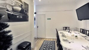 A dining area with a white table set for four, a black and white rug, and a framed picture on the wall. - Magical & Charming 8 rooms Covent Garden TownHouse (London)